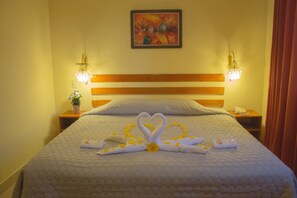 Una habitación de hotel con una cama, un cuadro en la pared y dos lámparas de noche.