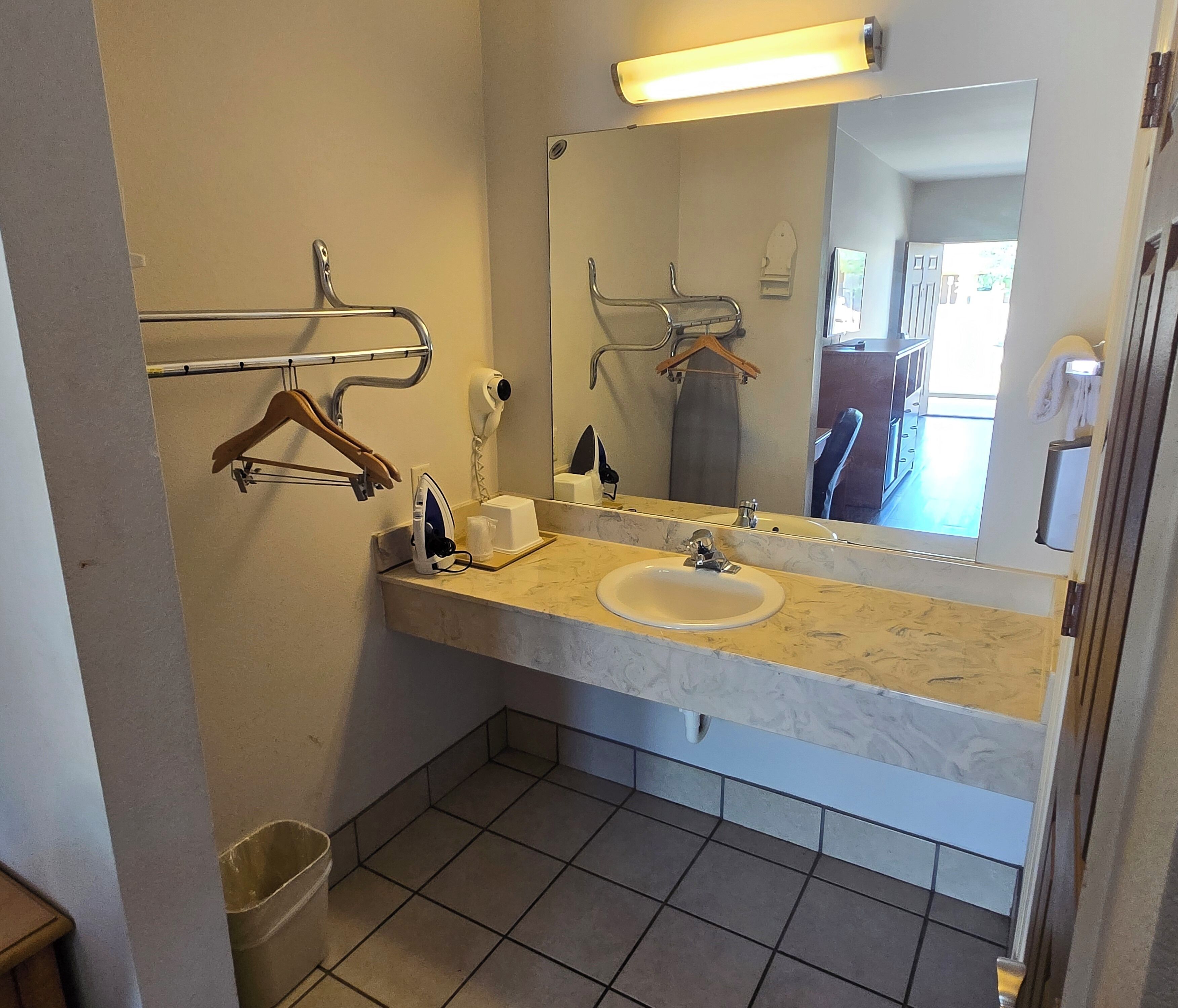 Un baño con lavabo, espejo, toallero y una toalla colgada.
