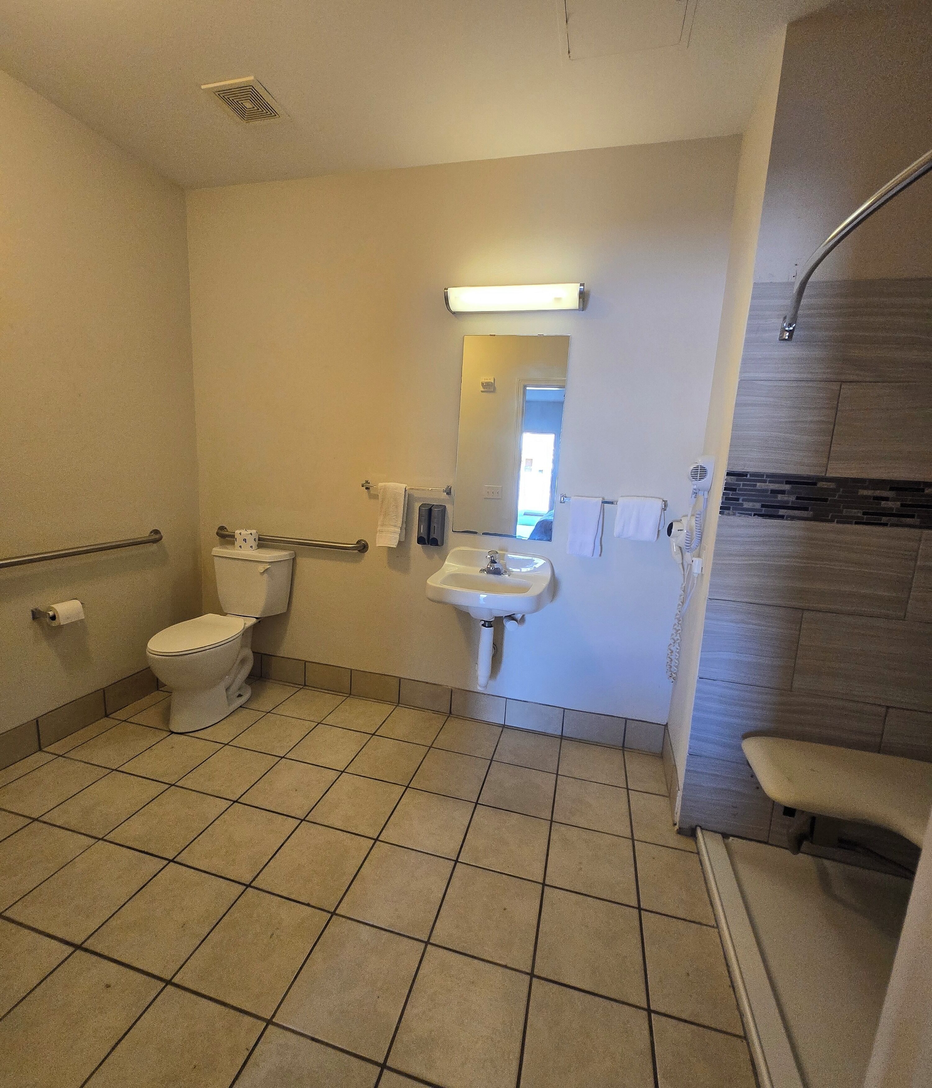 Un baño con inodoro, lavamanos y zona de ducha.