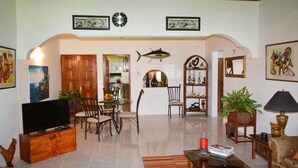 A living room with a TV, chairs, a coffee table, and a bookshelf. - Cozy Coco (Negril)