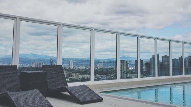 A rooftop pool area with lounge chairs and a cityscape view. - Vista Shaw by Charles (Mandaluyong)