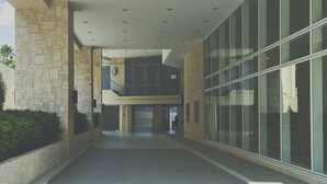 A modern building with a covered walkway, stone walls, and large glass windows. - Vista Shaw by Charles (Mandaluyong)