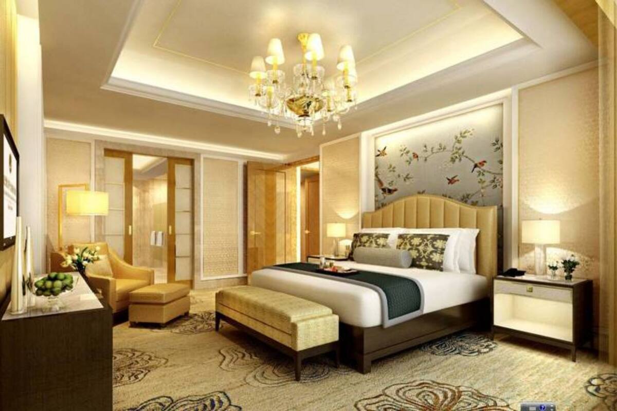 Ruime hotelkamer met een groot bed, een zithoek met een stoel en een tafeltje, een bureau en een kroonluchter.