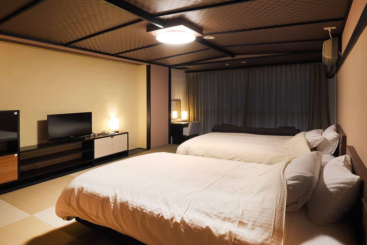 A hotel room with a large bed, a TV, a desk, and a lamp.