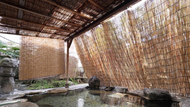 A traditional Japanese onsen with a bamboo screen wall, clear hot spring water, and stone seating. - Tokiwa Hotel (Nasushiobara)