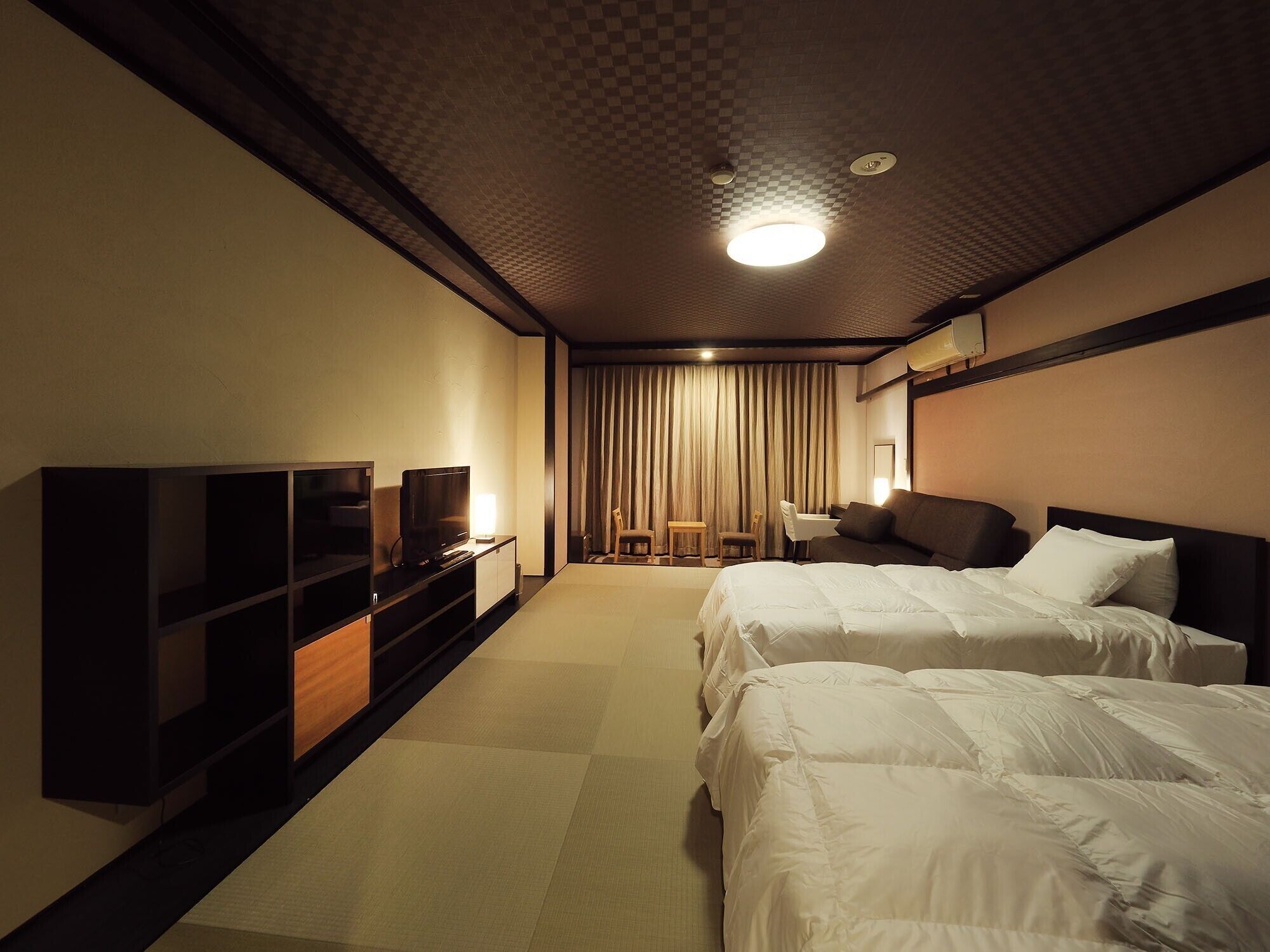 A hotel room with two beds, a TV, a desk, and a chair.