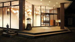 A modern building with large glass windows, a covered entrance, and a small outdoor seating area. - Tokiwa Hotel (Nasushiobara)