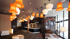 A modern hotel lobby with multiple seating areas, a reception desk, and large windows providing natural light. - Tokiwa Hotel (Nasushiobara)