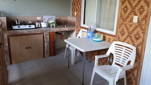 Cozinha compacta com fogão a gás, pia e cadeiras brancas.