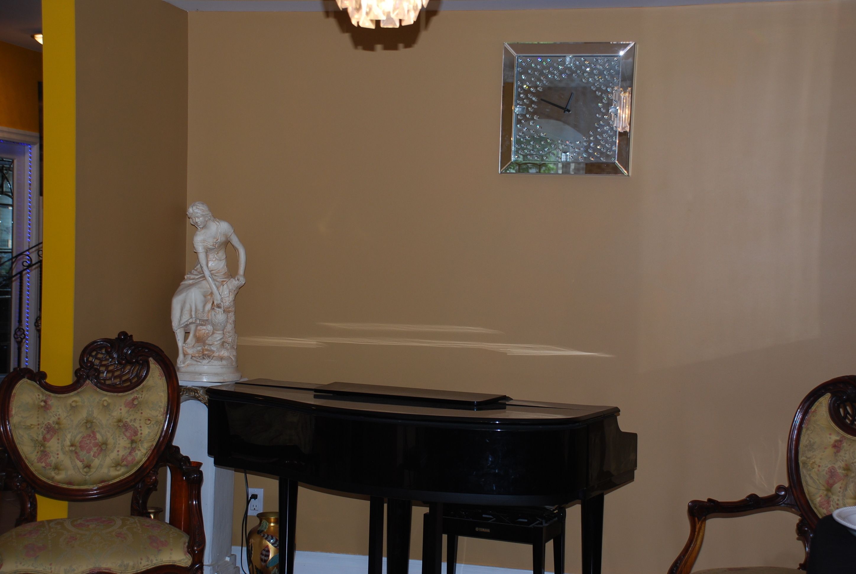 Une pièce avec un piano, une statue et une horloge au mur.