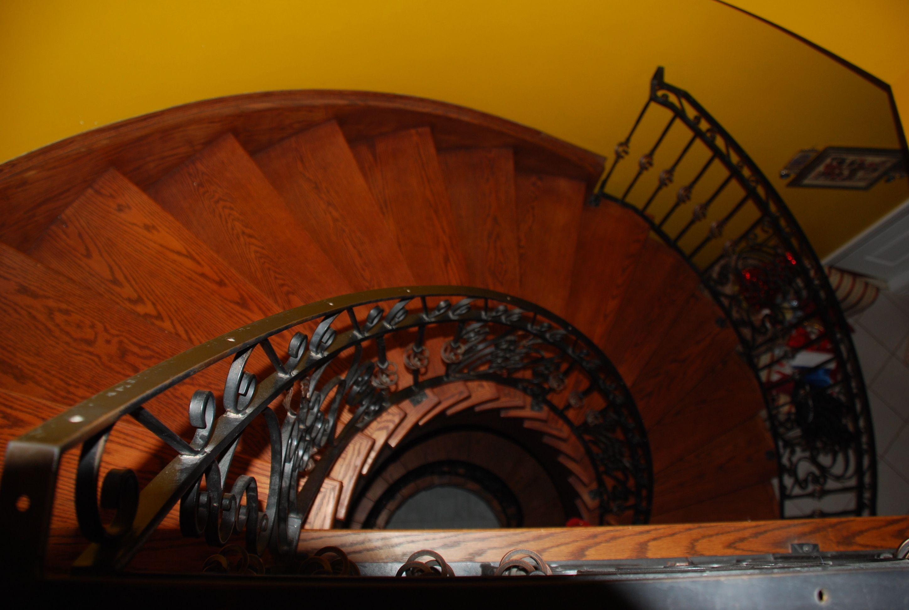 A spiral staircase with wooden steps and ornate metal railings.