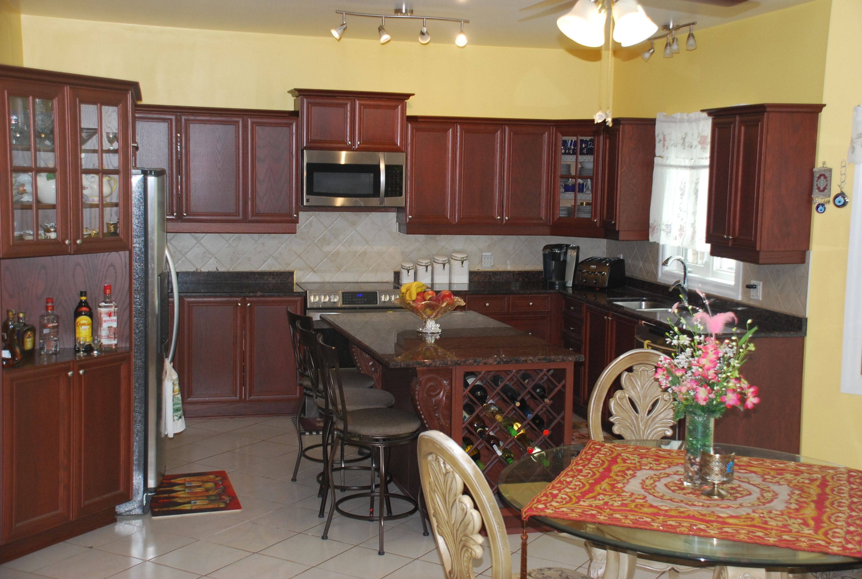 A kitchen with wooden cabinets, a microwave, a wine rack, and a dining area with a table and chairs.