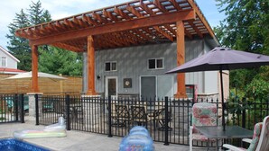Un patio techado con piscina, mobiliario exterior y una pérgola.