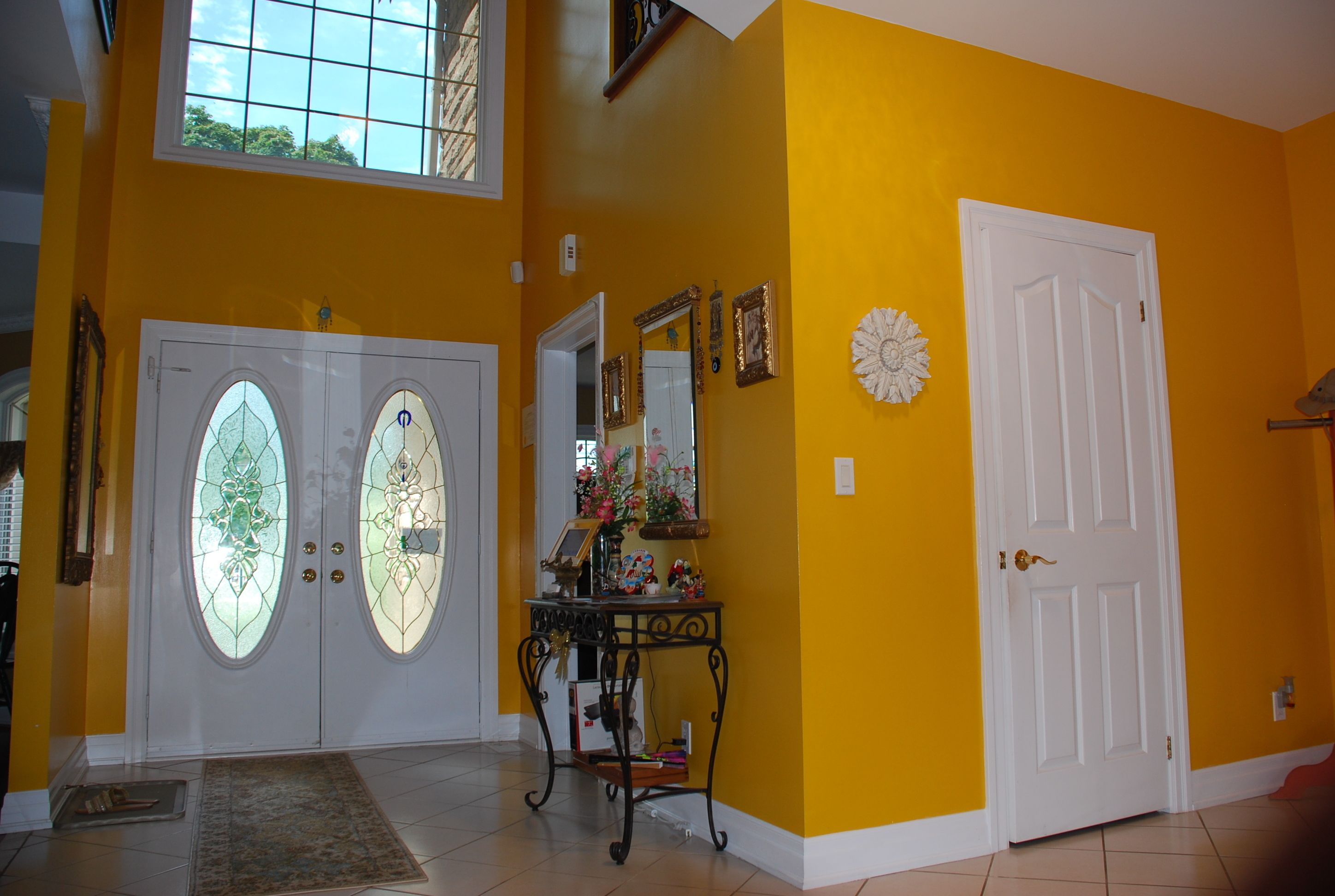 A hallway with yellow walls, a white door, and a double door with glass panels.