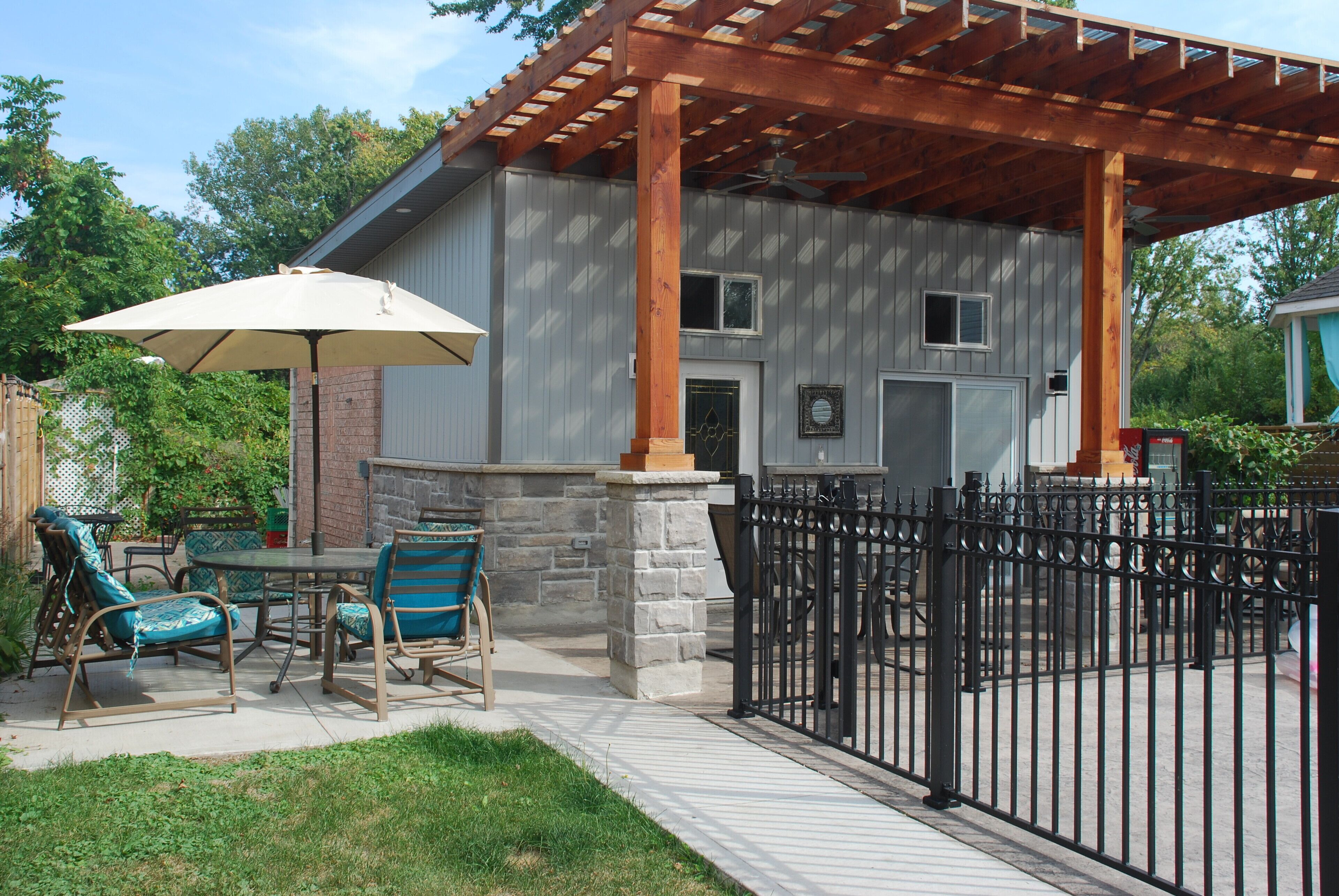 Un patio cubierto con mobiliario exterior, una pérgola y una columna de piedra.