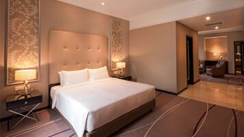 A hotel room with a large bed, two bedside tables with lamps, a headboard, and a carpeted floor.