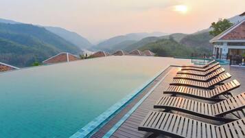 Una piscina con tumbonas de madera y vistas a las montañas.