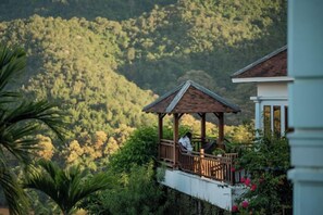 A gazebo with a person sitting, overlooking a lush green hillside.