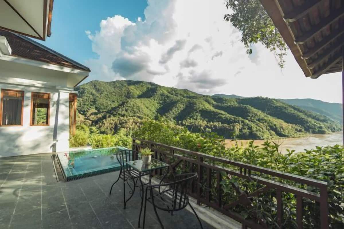 Eine Terrasse mit Pool, Stühlen und Blick auf einen Fluss und Berge.