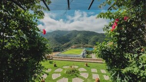 Un jardin avec une pelouse aux motifs géométriques, une piscine et une vue sur les montagnes.