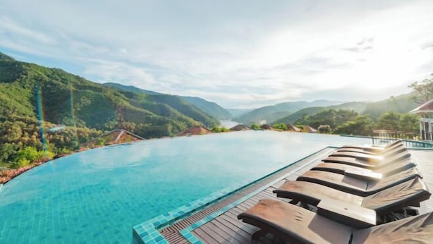 Un espace aménagé au bord de la piscine, avec des chaises longues et une vue sur les montagnes.
