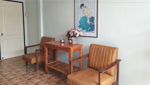 A room with a wooden table and two chairs, a framed picture on the wall, and a door with a number sign. - Baan Plubpla Resort (Chanthaburi)