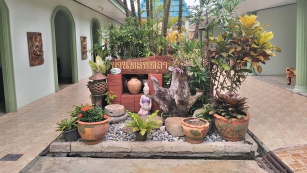A courtyard with a central wooden structure, potted plants, and a sign with Thai script. - Baan Plubpla Resort (Chanthaburi)