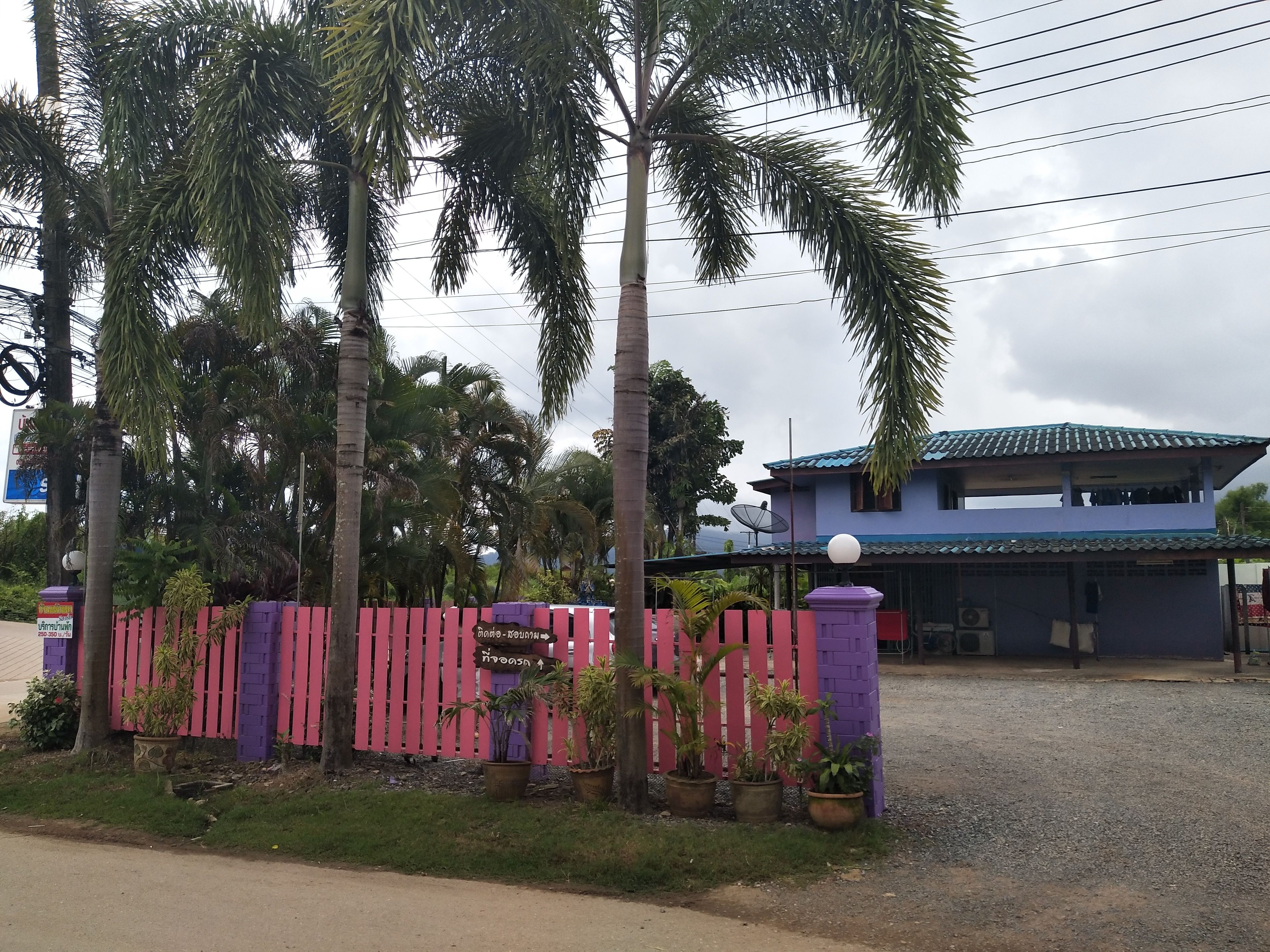 A two-story building with a blue roof and a purple fence in front.