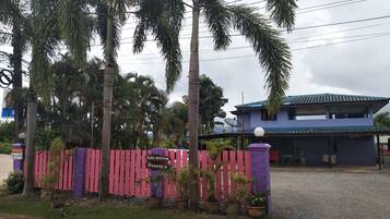 A two-story building with a blue roof and a purple fence in front.