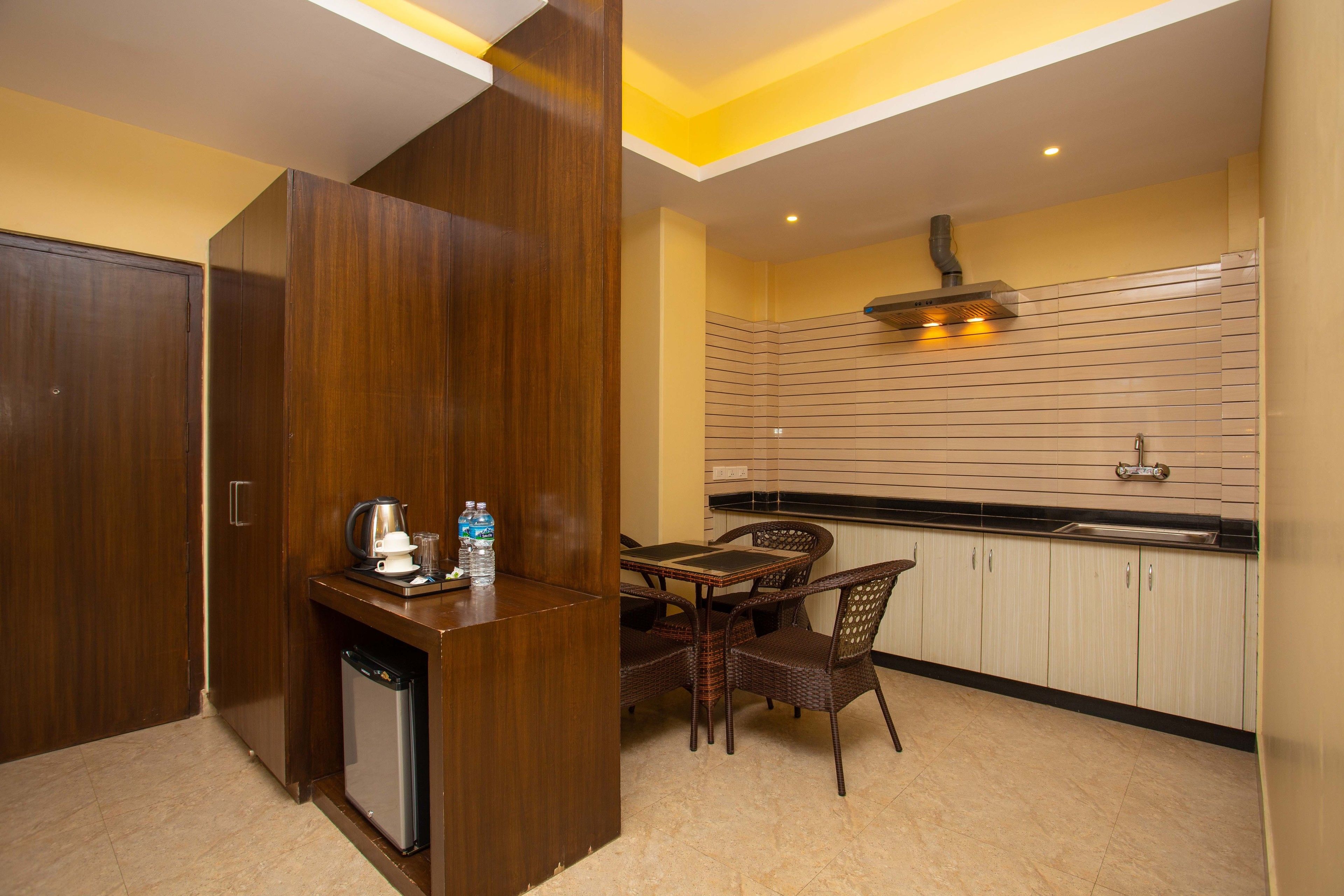 A compact kitchen with a dining area, featuring a built-in dishwasher, a coffee maker, and a water dispenser on the counter.