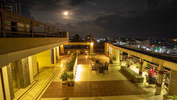 A rooftop terrace with outdoor seating, potted plants, and a view of the cityscape at night. - Hotel Lake Paradise (Pokhara)