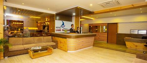 A hotel lobby with a reception desk, a sofa, a coffee table, and a bar area.