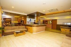 Un hall de hotel con una recepción, un sofá, una mesa de centro y una zona de bar.