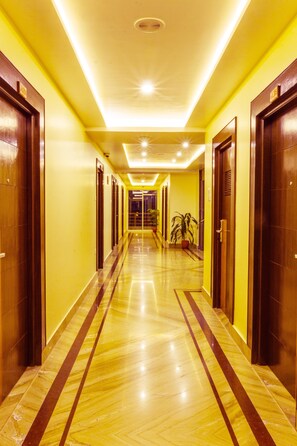 A hotel corridor with wooden doors, yellow walls, and a shiny marble floor. - Hotel Lake Paradise (Pokhara)