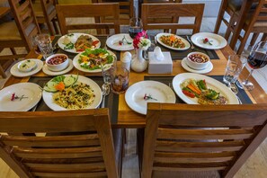 A dining table set with plates of food, glasses, and cutlery.
