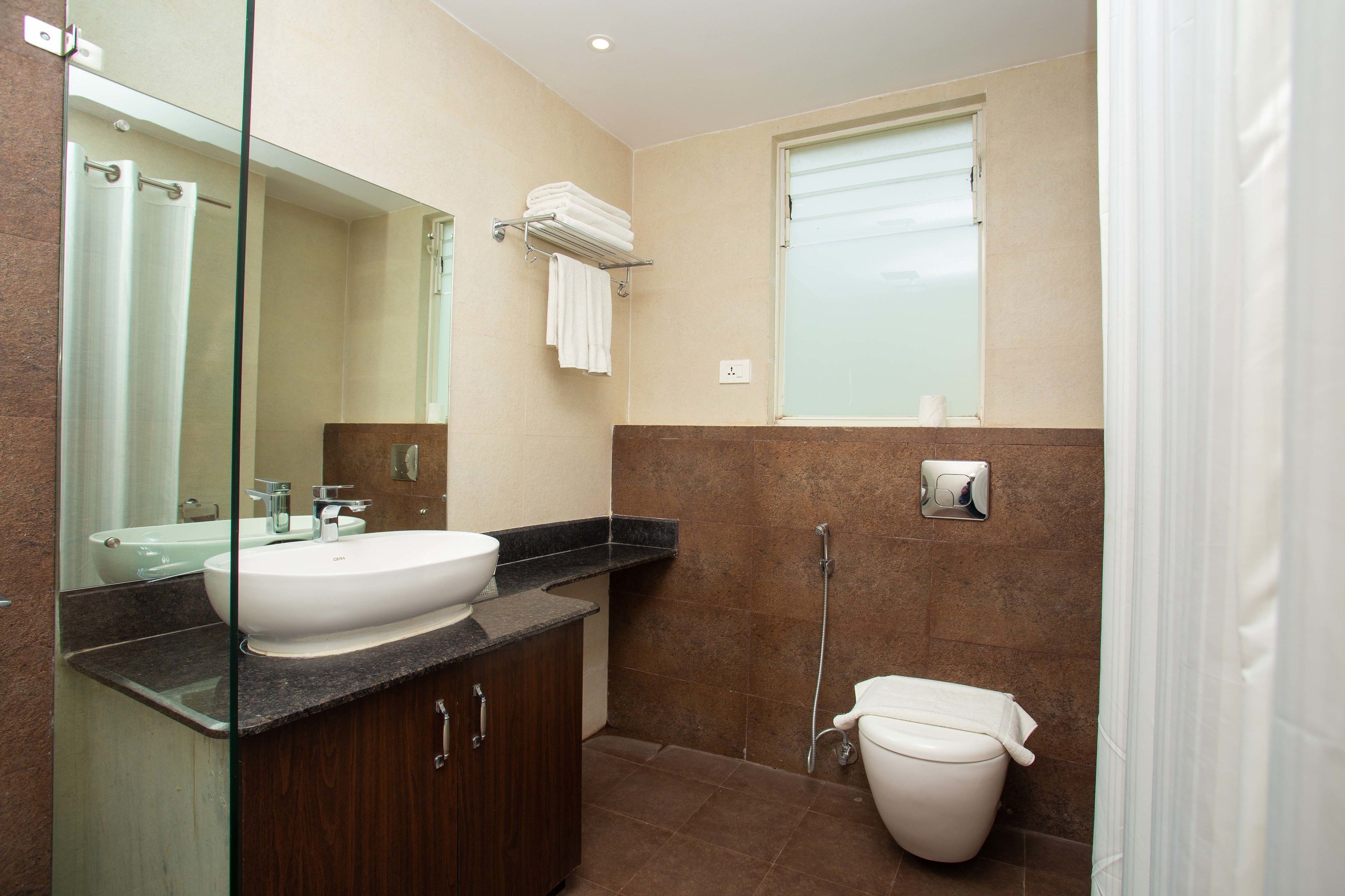 Un baño con lavamanos, espejo, ducha e inodoro.