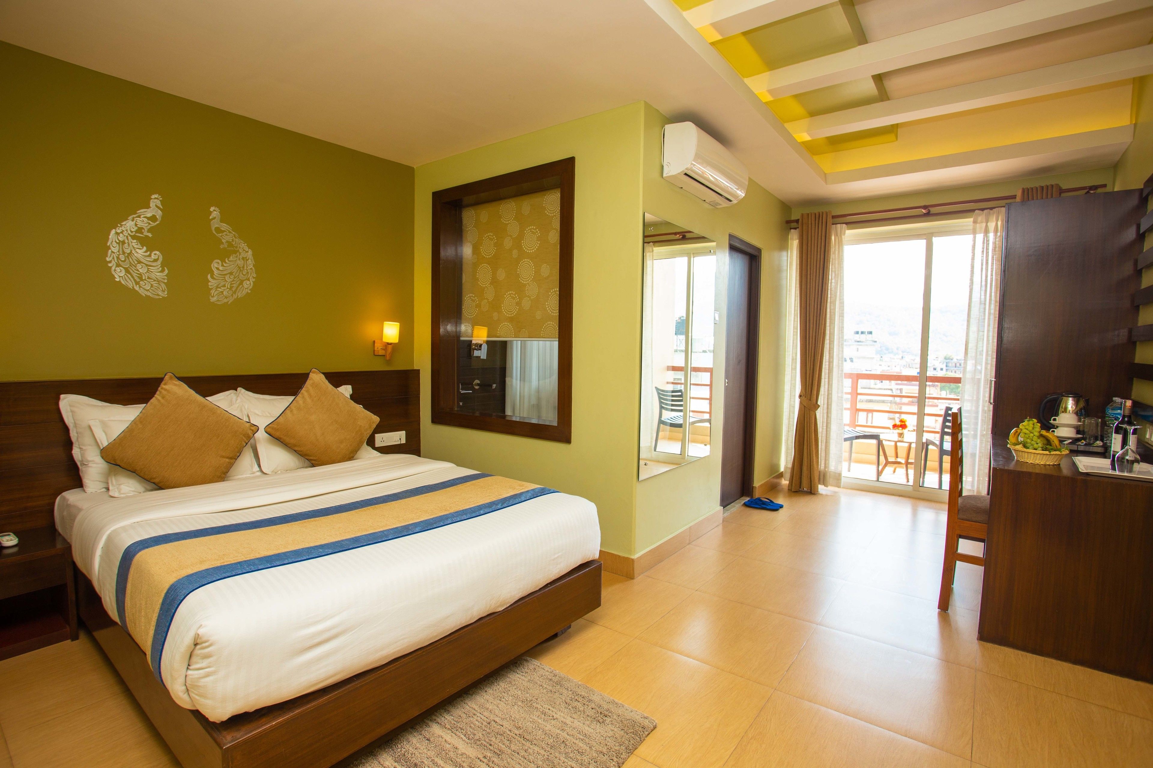A hotel room with a bed, a desk, and a balcony with a view.