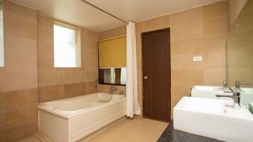 A modern bathroom with a bathtub, two sinks, and a large mirror.