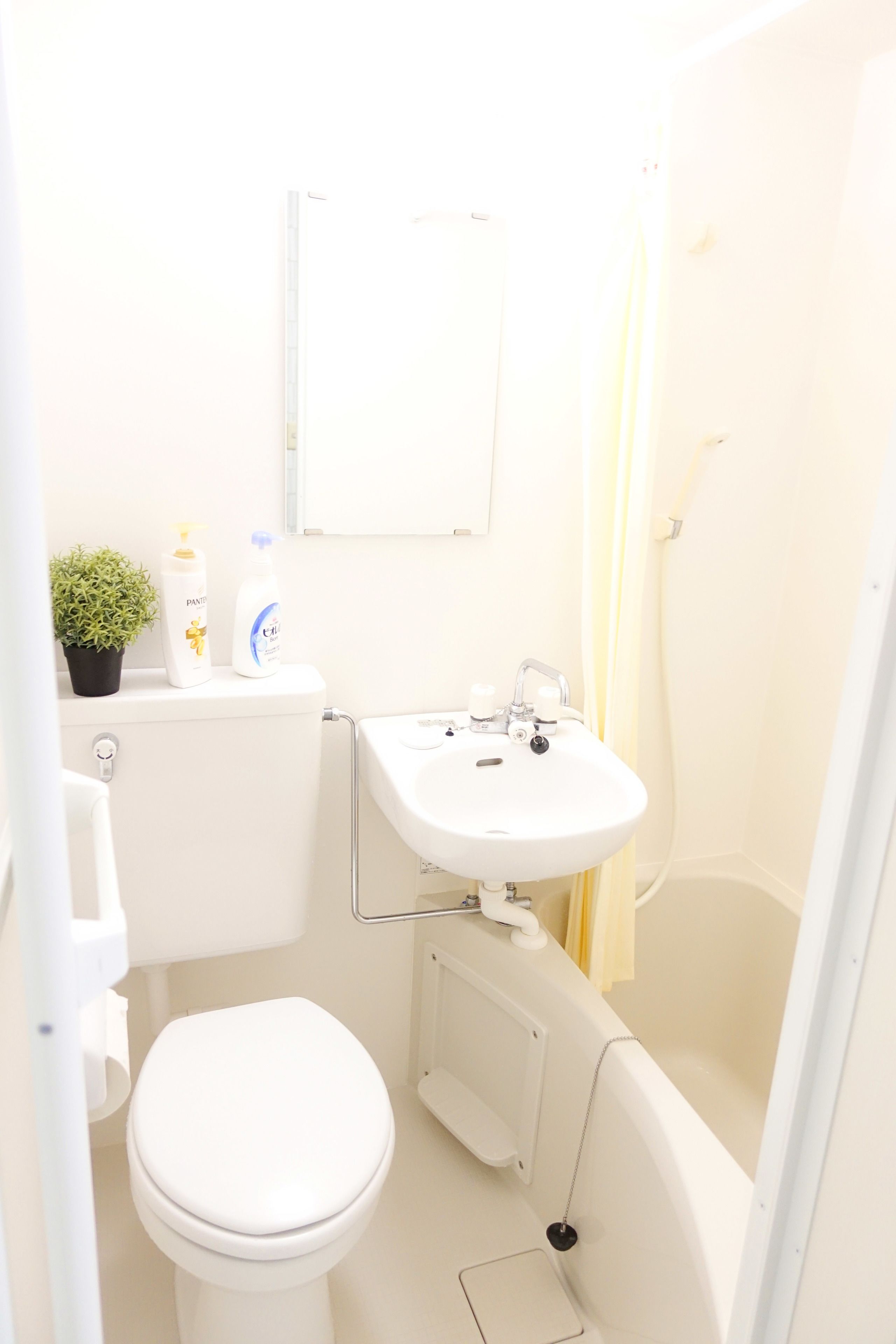 Un baño pequeño y luminoso con inodoro, lavabo y ducha.