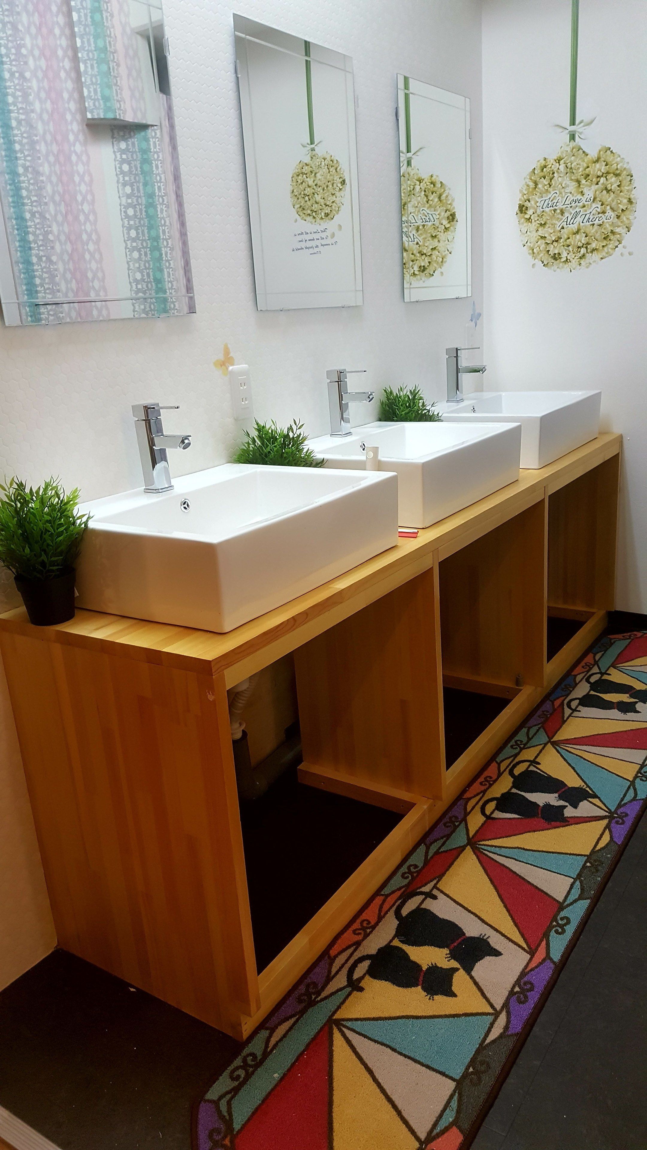 A bathroom with two sinks, a mirror, and a decorative wall hanging.