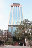 Un edificio alto y moderno con ventanas amplias y una entrada central.
