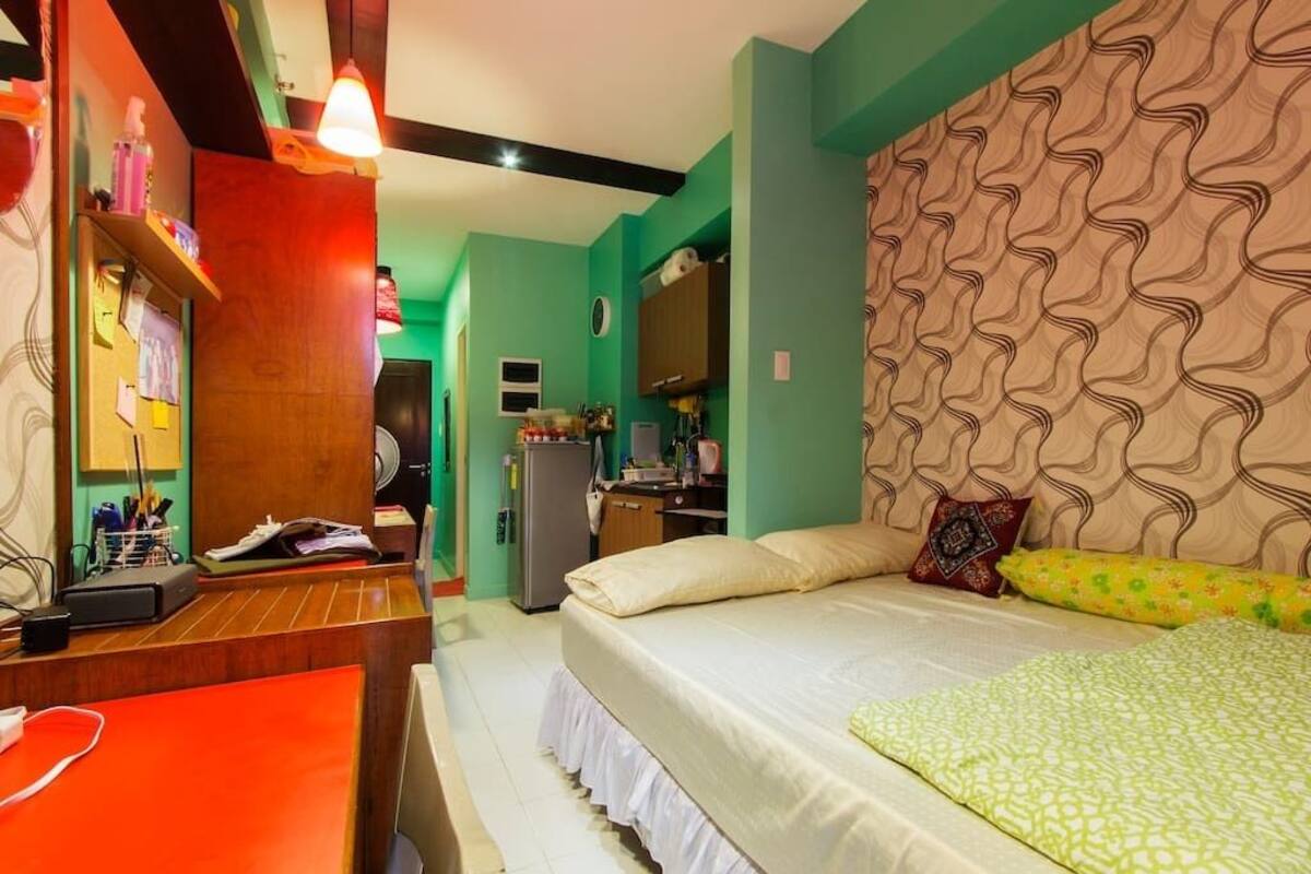 A hotel room with a bed, a desk, a mirror, and a wardrobe.