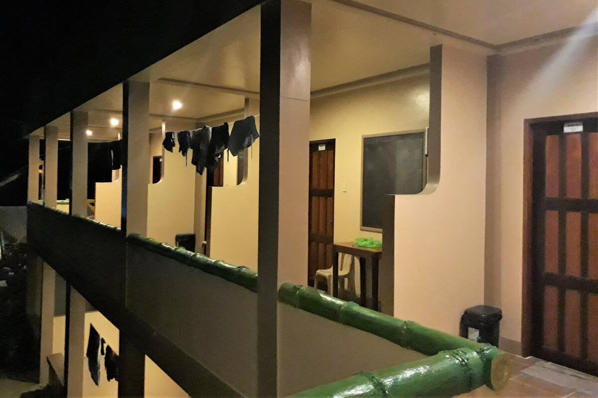 Un escalier avec une rampe verte mène à une pièce qui contient un lit, une fenêtre et une porte.