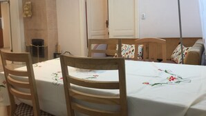 A dining area with a table set for two, wooden chairs, and a sofa with floral cushions. - Heart of Riga Apartment (Riga)