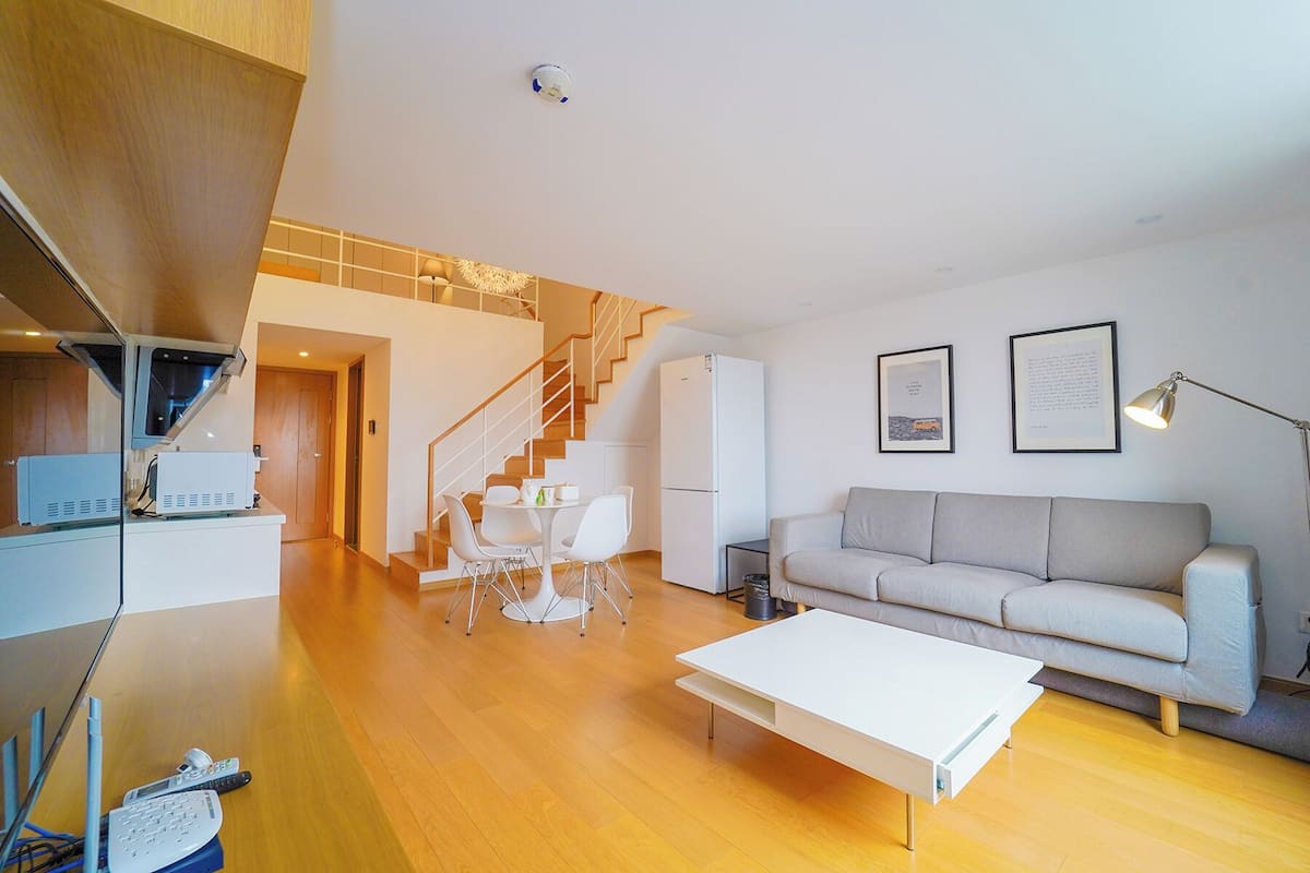 A modern living room with a sofa, coffee table, and a staircase leading to an upper level.