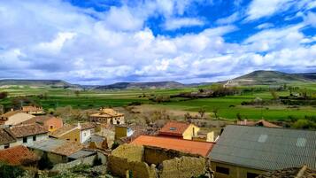 A rural village with traditional stone buildings and a view of green fields and hills in the distance.