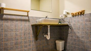 A bathroom with a sink, mirror, toilet, and patterned floor tiles.