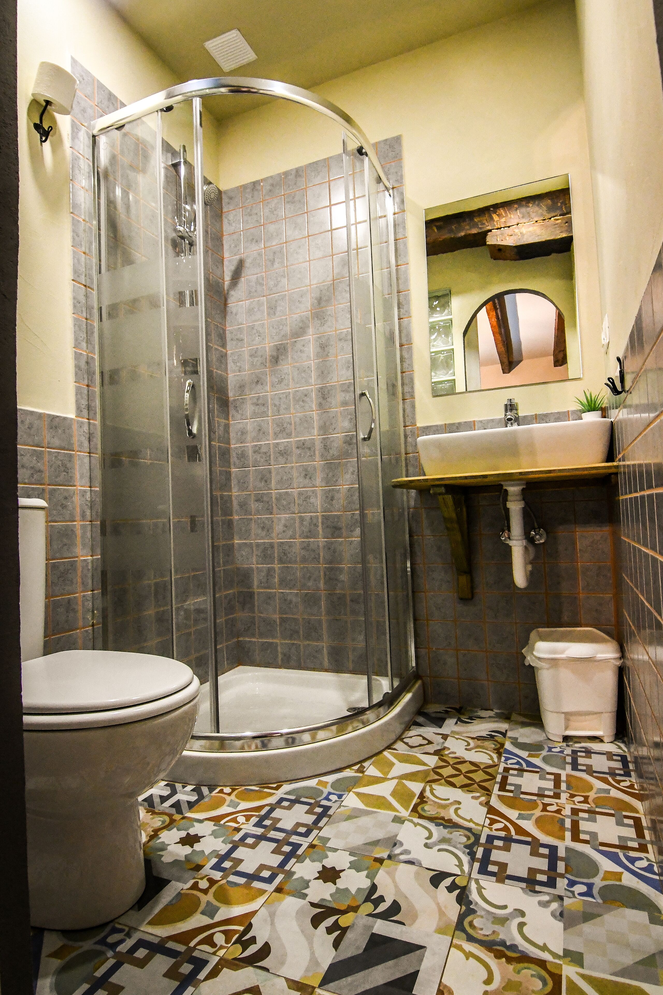 Een badkamer met douche, toilet, wastafel en betegelde vloer.