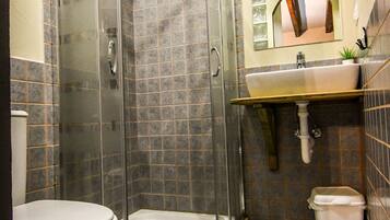 Een badkamer met douche, toilet, wastafel en betegelde vloer.