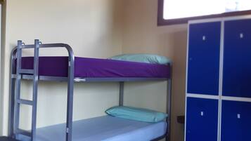 A bunk bed with a ladder, a small wooden bench, and blue lockers.